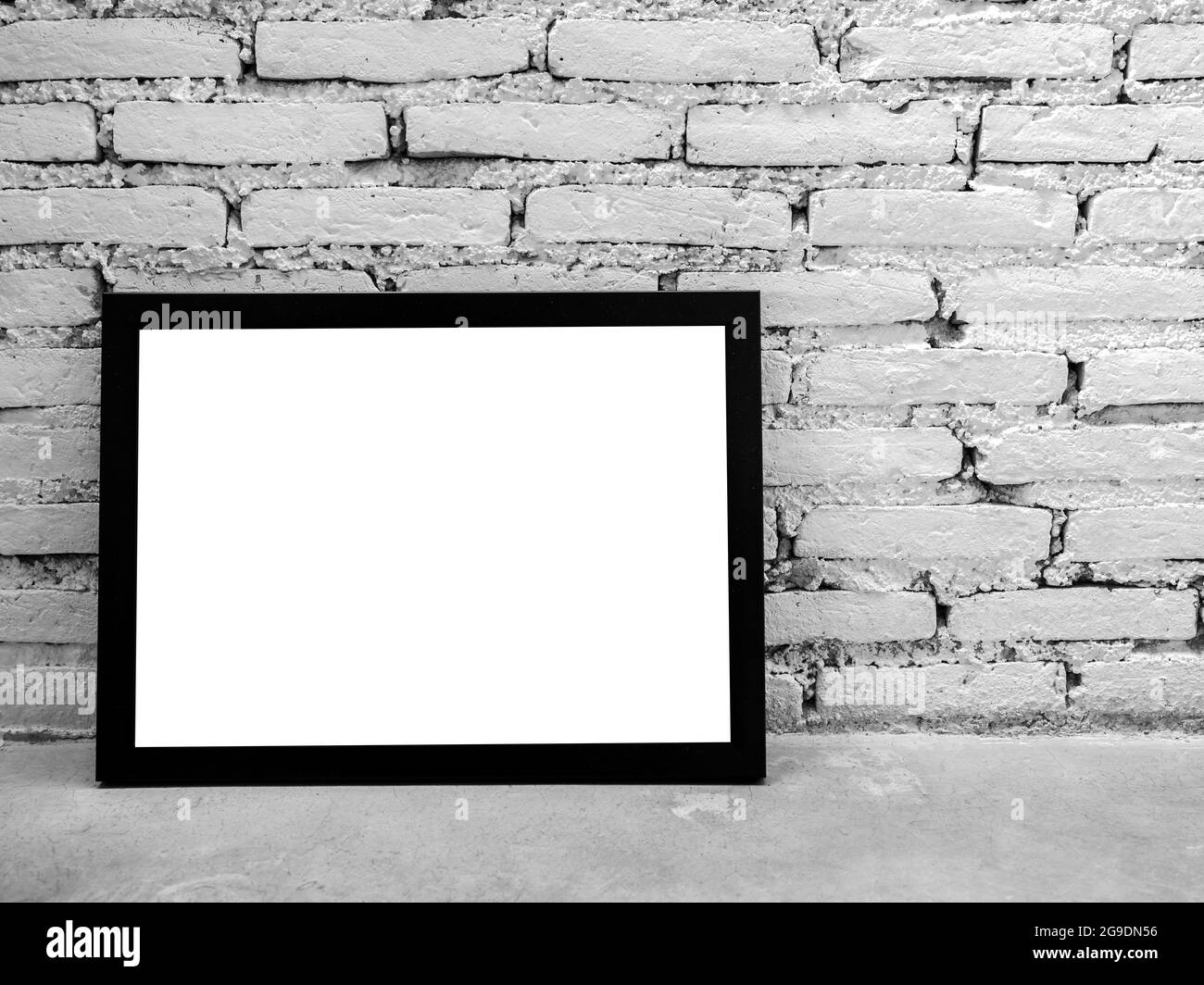 Cornice fotografica mockup. Immagine quadrata bianca con mockup nero su ripiano in cemento e sfondo bianco in mattoni con spazio per la copia. Foto Stock