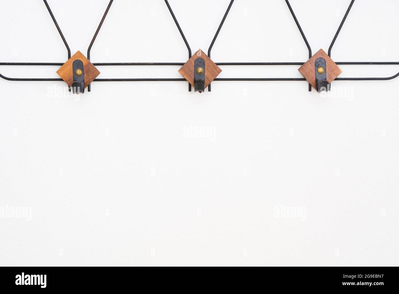 Appendiabiti vuoto con elementi in metallo nero ed elementi in legno sulla parete bianca testurizzata Foto Stock