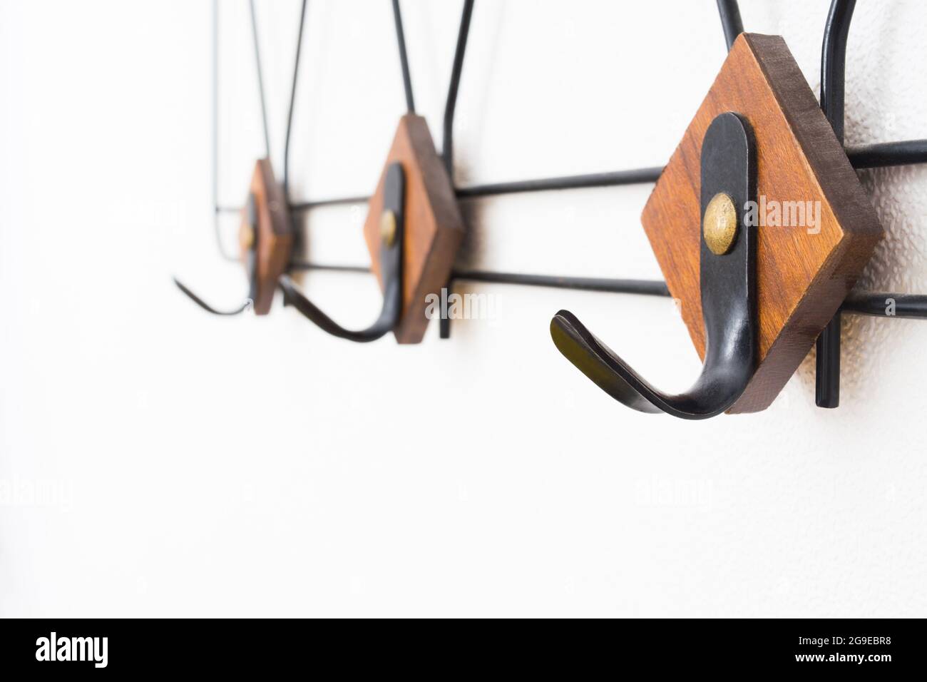 Appendiabiti vuoto con elementi in metallo nero ed elementi in legno sulla parete bianca testurizzata Foto Stock