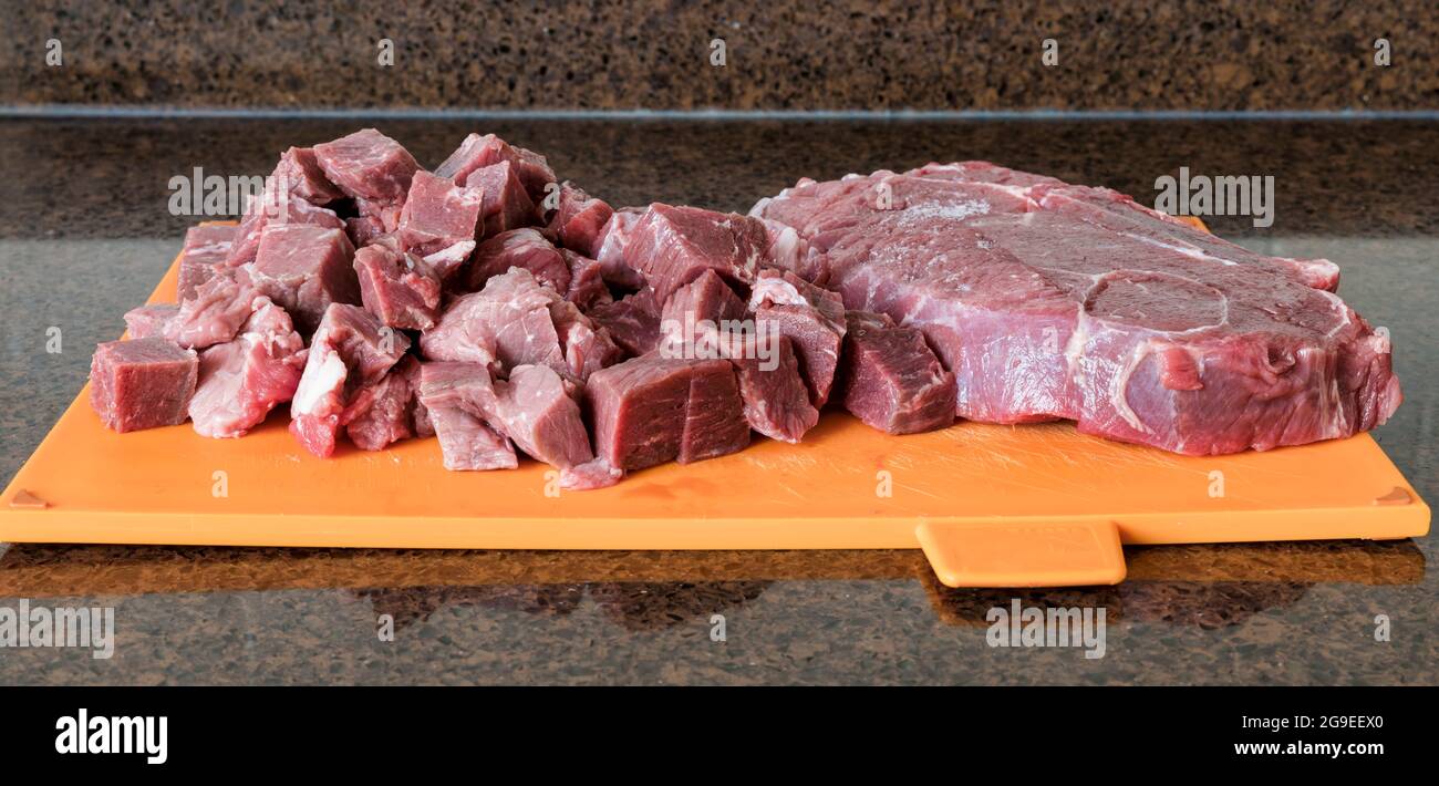 Un bel pezzo magro di carni bovine è tagliato a pezzi in cucina per preparare un piatto a base di carne Foto Stock