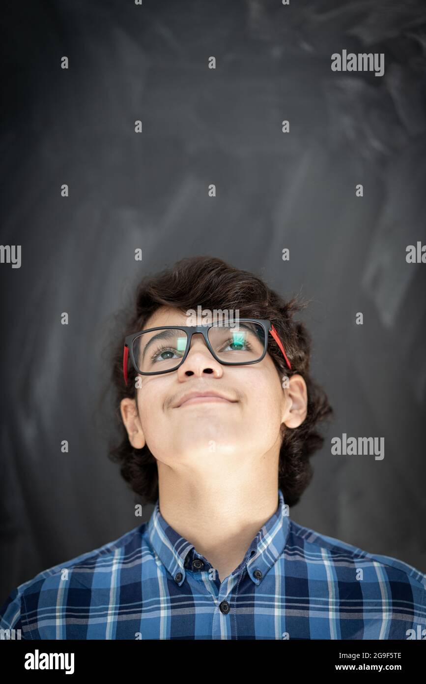 Ragazzo adolescente con occhiali di fronte alla lavagna in classe Foto Stock