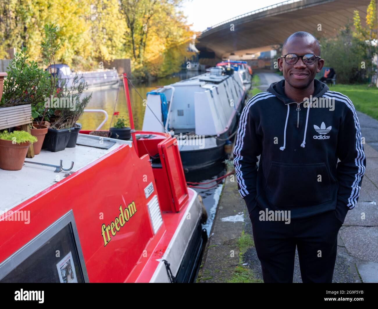 Un uomo nero su una barca stretta lungo il canale del Rent a Little Venice, Londra Foto Stock