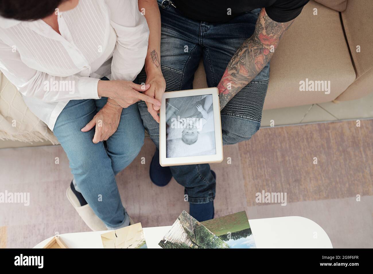 Vista ad alto angolo di madre che mostra al figlio la sua vecchia foto mentre si siedono sul divano in camera Foto Stock