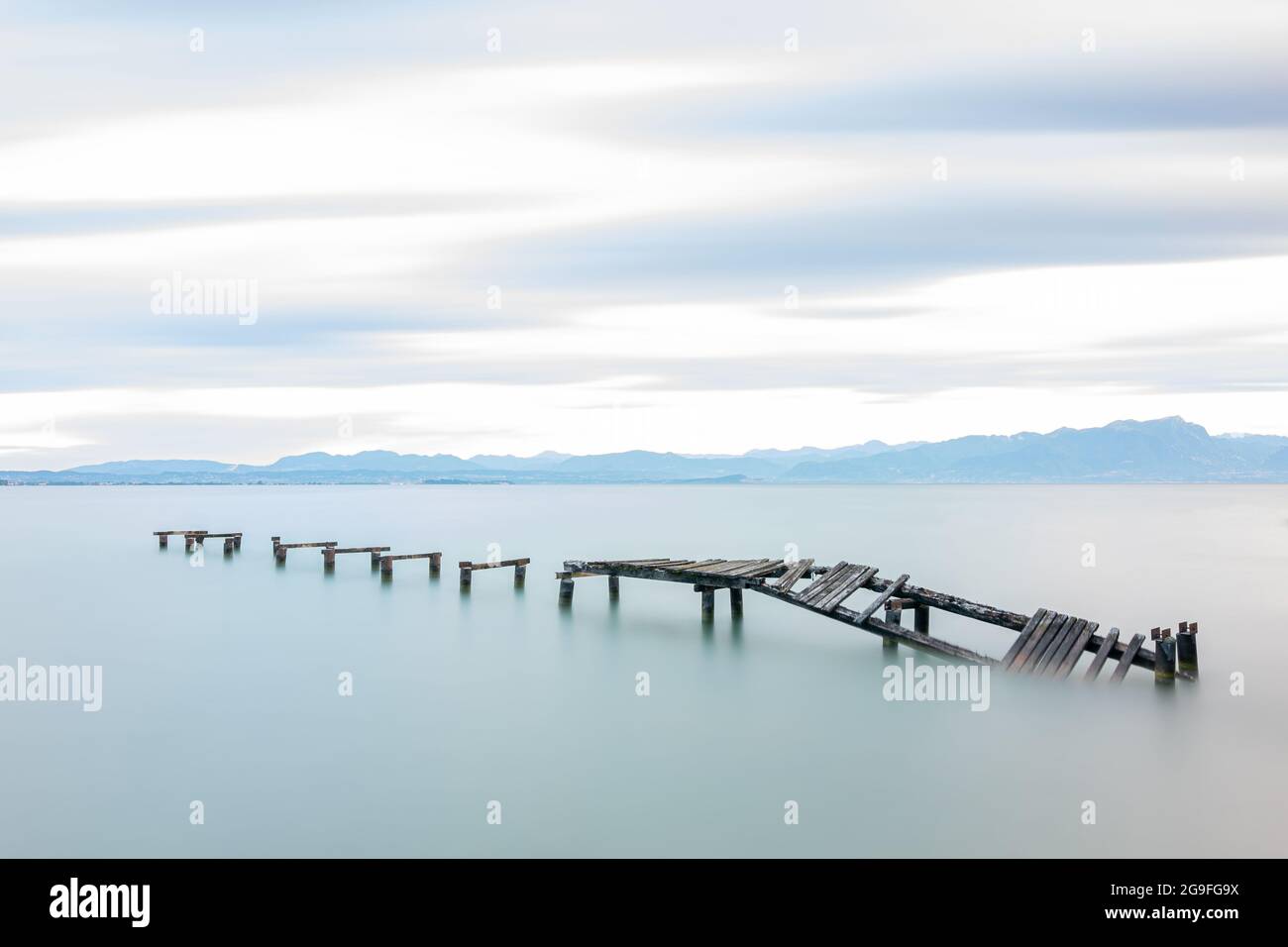 Molo in legno abbandonato in lago durante l'alba, lunga esposizione Foto Stock