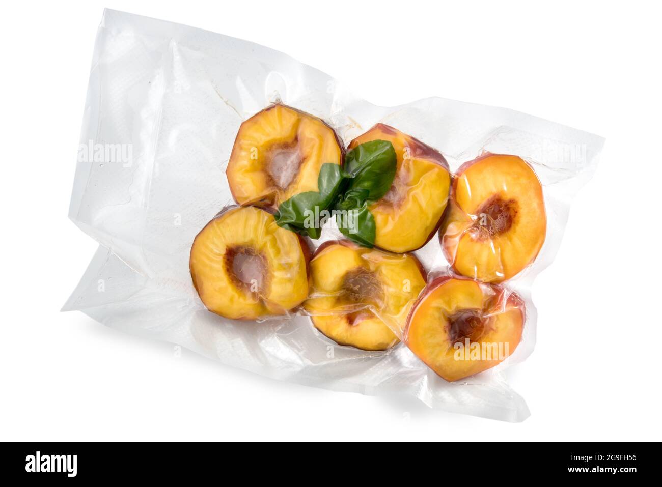 Pesche tagliate a metà con foglie di menta confezionate sotto vuoto sigillate per cottura sous vide isolate su bianco Foto Stock