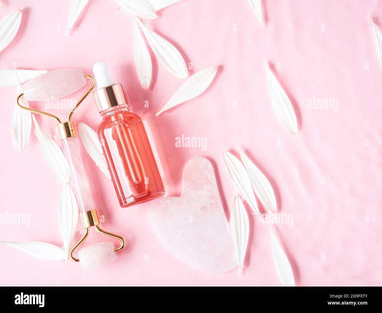 Bellezza cosmetica olio siero prodotto acido bottiglia e guasha rullo viso al quarzo su sfondo rosa Foto Stock