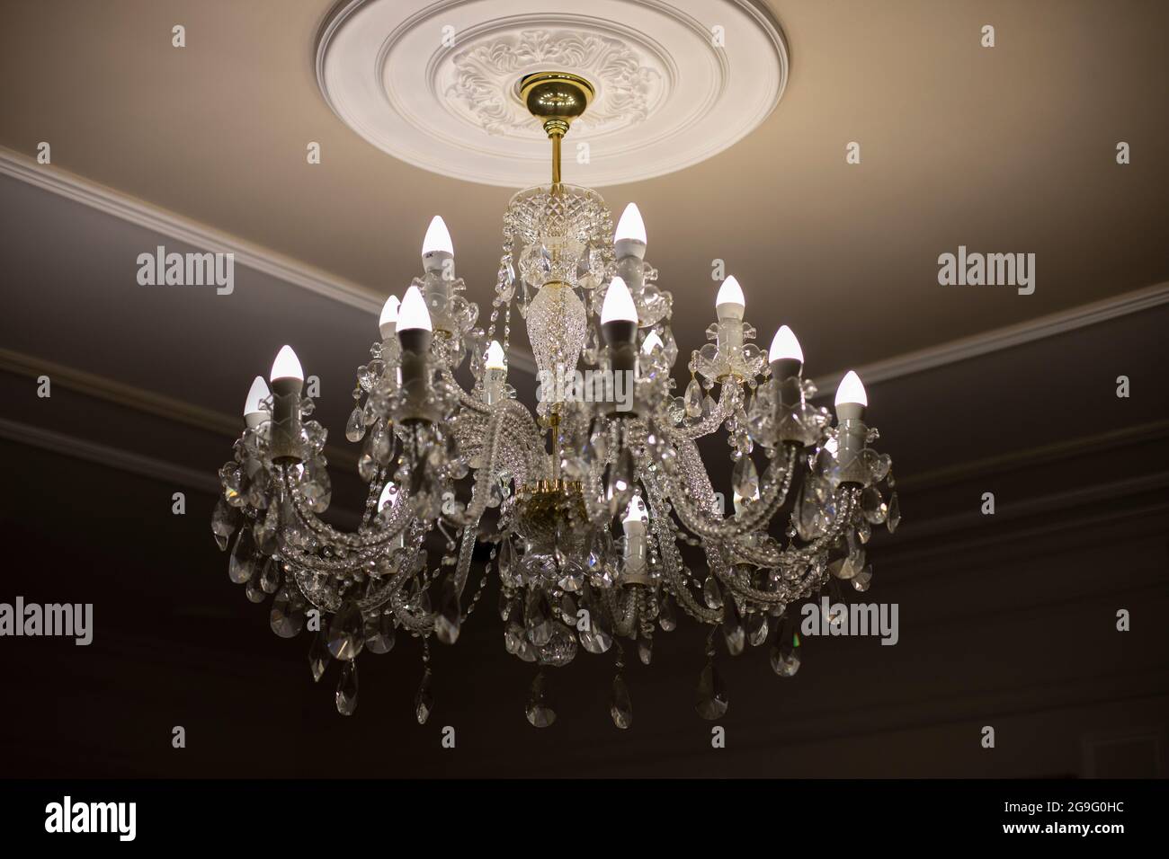 Lampadario in vetro. Sorgente luminosa da soffitto. Le lampade brillano attraverso un lampadario d'epoca. Foto Stock