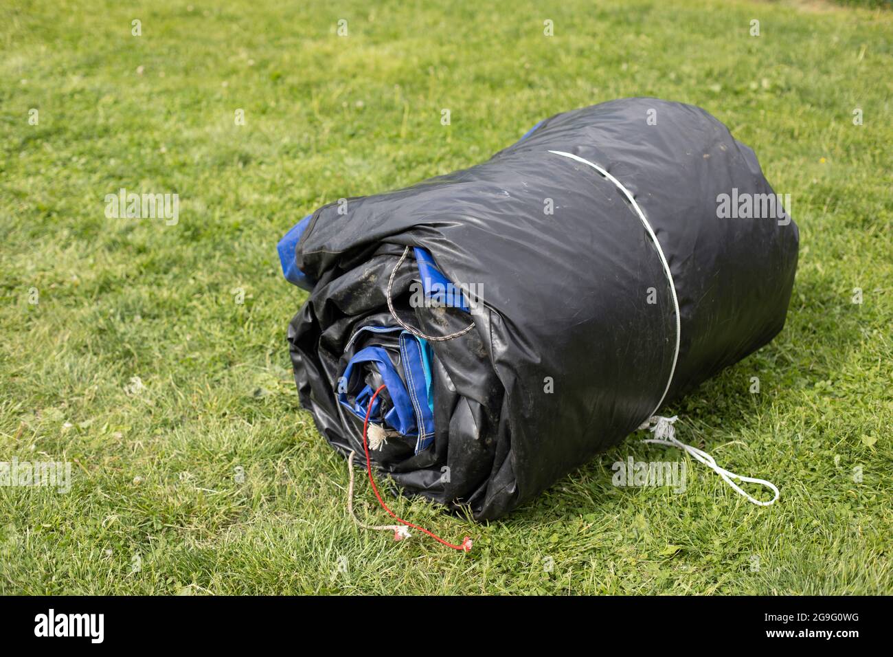 Materiale in gomma attorcigliata. La tenda per pioggia è ripiegata. La struttura gonfiabile è pronta per il trasporto e il carico. Foto Stock