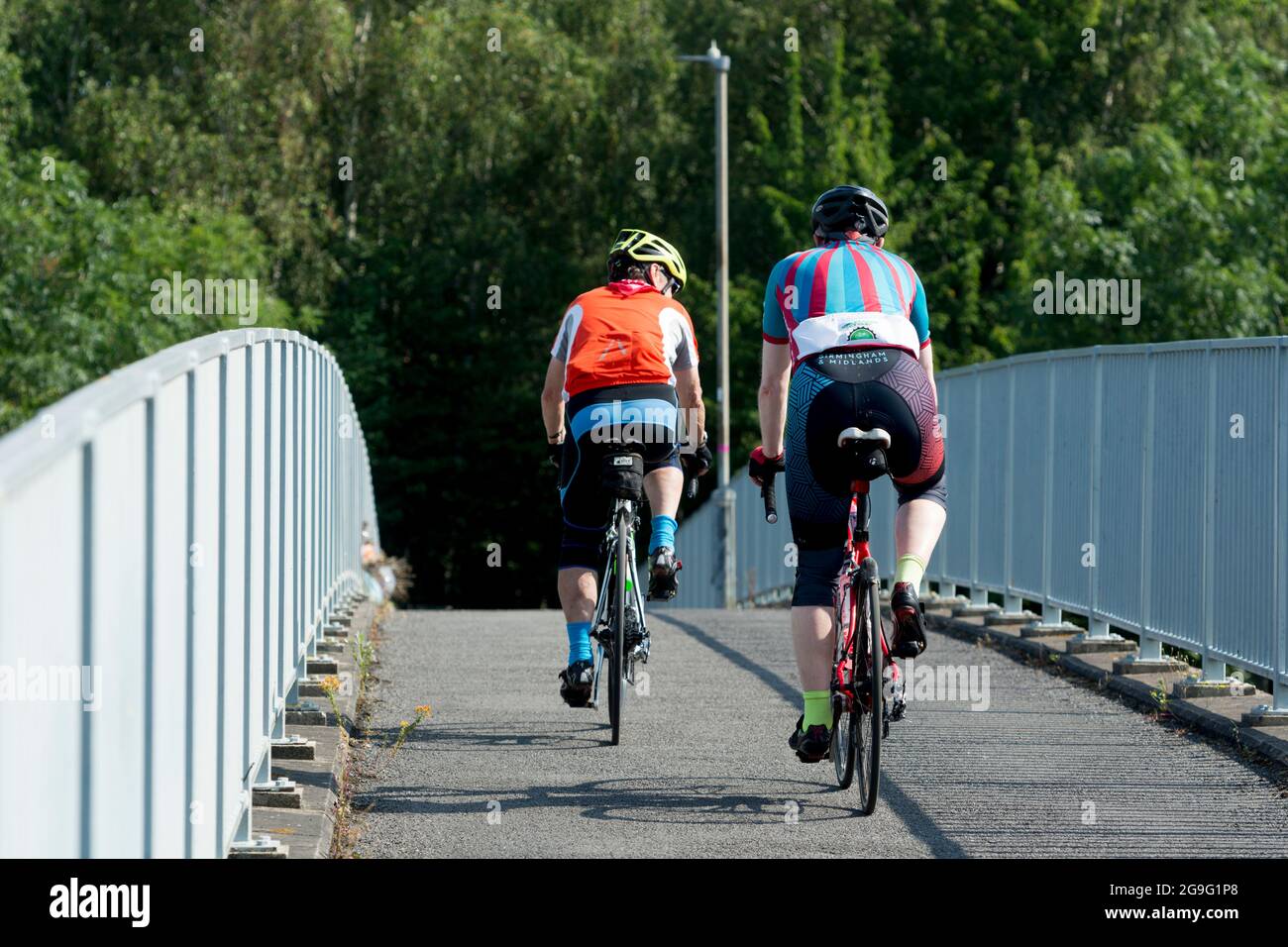Due ciclisti che attraversano un ponte pedonale/ciclabile, Warwickshire, Regno Unito Foto Stock