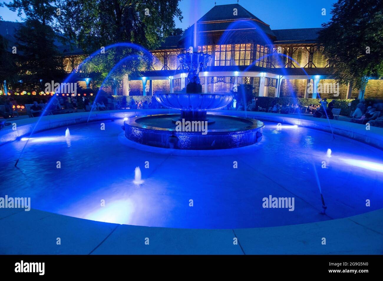 Spa giardino illuminazione nel giardino termale reale Bad Reichenhall. La fontana illuminata Solebrunnen di fronte alla casa di laurea. Bad Reichenhall, Baviera, Germania. Foto Stock