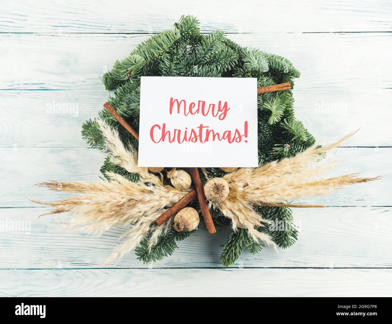 Naturale natale abete rosso arida decorazione wreath con biglietto d'auguri bianco con testo Merry Christmas Foto Stock