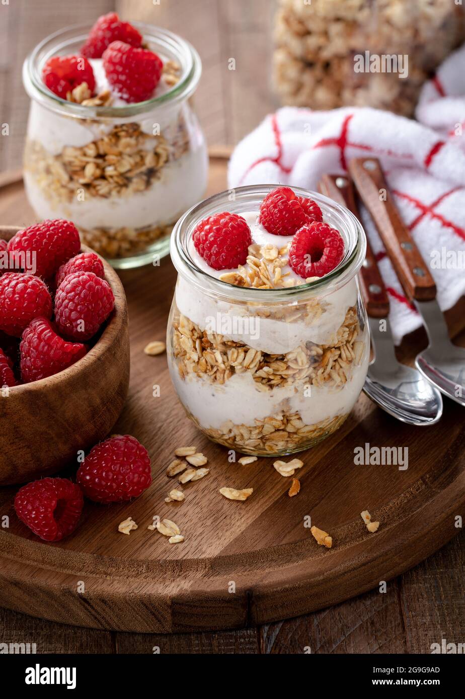 Parfait di granola con yogurt e lamponi freschi su un piatto di legno Foto Stock