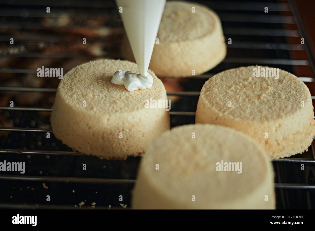 Torta di cottura. Donna spreme la panna su una torta. Decorazioni per torte. Foto Stock