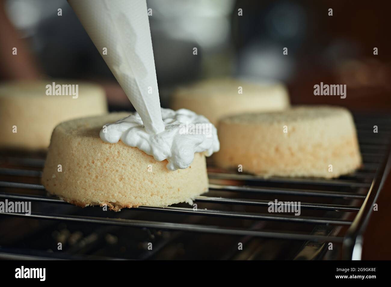 Torta di cottura. Donna spreme la panna su una torta. Decorazioni per torte. Foto Stock