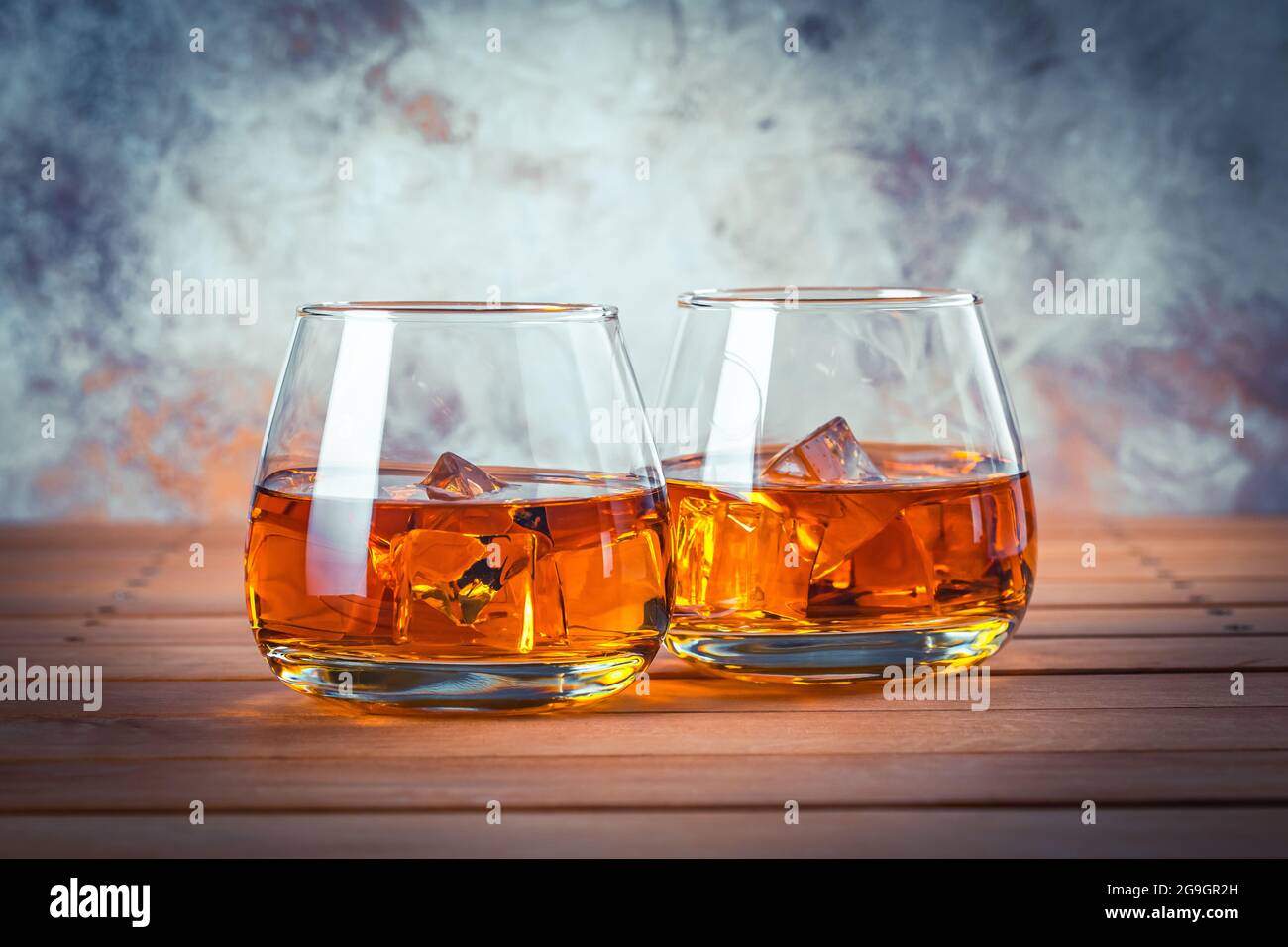 Due bicchieri di whisky con ghiaccio. Vita morta. Brandy, borbone su un tavolo di legno marrone. Bevanda alcolica forte. Rum, scotch Foto Stock