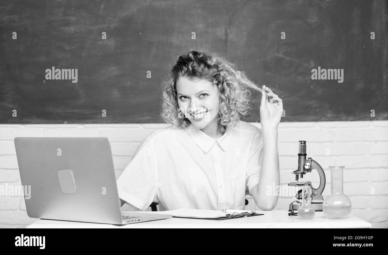 affascinante lezione di biologia. esperimento di biologia. prendere appunti sui risultati della ricerca chimica. felice studente con microscopio e bicchiere. ragazza dentro Foto Stock