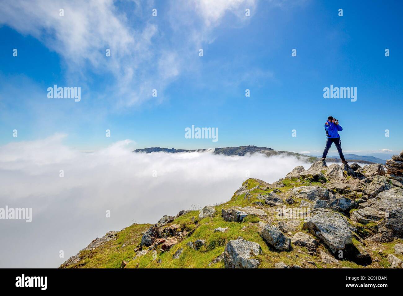 Snowdonia, Regno Unito. 15 luglio 2021. Con un numero sempre maggiore di persone in vacanza nel Regno Unito, la catena montuosa Snowdonia offre una vista mozzafiato per coloro che desiderano una vacanza all'insegna dell'avventura. Un escursionista mostrato qui dopo aver raggiunto la cima di Y Garn godendo del sole glorioso come scatta fotografie della cima con le nuvole che coprono la valle sottostante. Credito: Lee Hudson Foto Stock