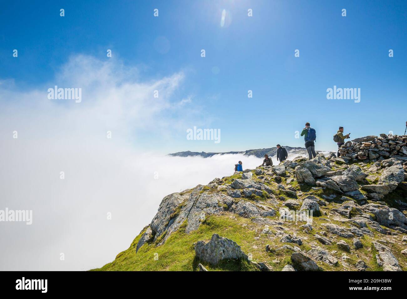 Snowdonia, Regno Unito. 15 luglio 2021. Con un numero sempre maggiore di persone in vacanza nel Regno Unito, le montagne gallesi del Parco Nazionale di Snowdonia nel Galles del Nord offrono alcune viste spettacolari e mozzafiato per coloro che vogliono una vacanza all'avventura. Gli escursionisti sono catturati qui dopo aver raggiunto con successo la cima di Y Garn godendo del sole glorioso mentre guardano giù nella valle nuvolosa ora ben al di sotto di loro! Credito: Lee Hudson Foto Stock