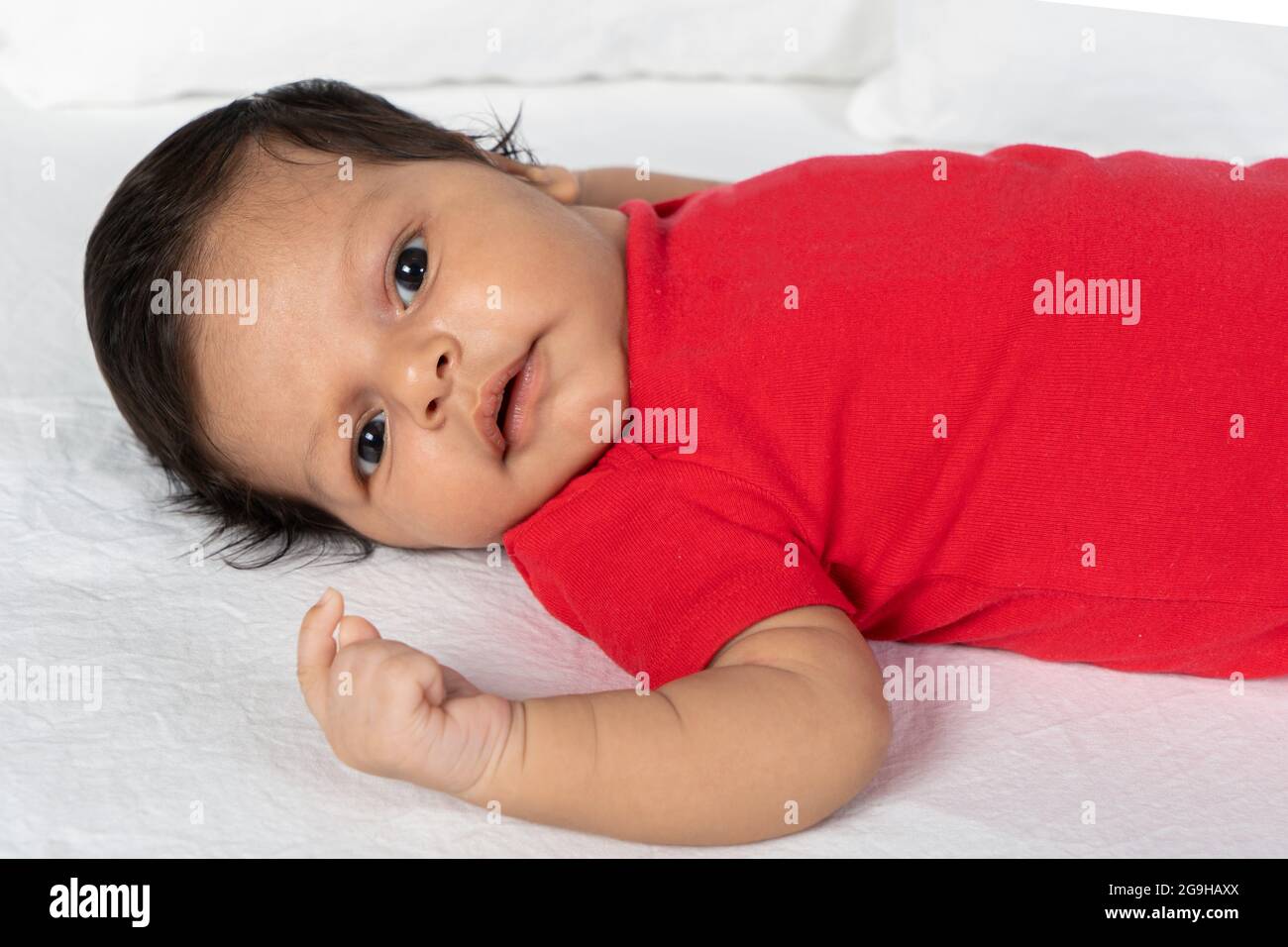 Bambino neonato sdraiato sulla schiena. Indossare abiti rossi Foto stock -  Alamy
