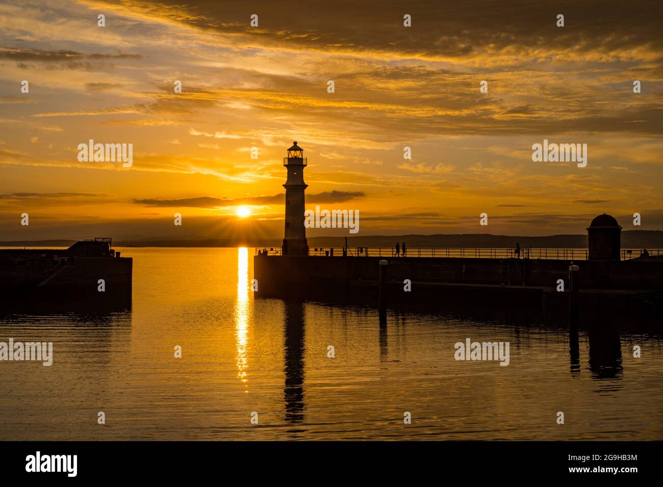 Il faro del porto di Newhaven si trova in un colorato cielo arancione al tramonto, Edimburgo, Scozia, Regno Unito Foto Stock