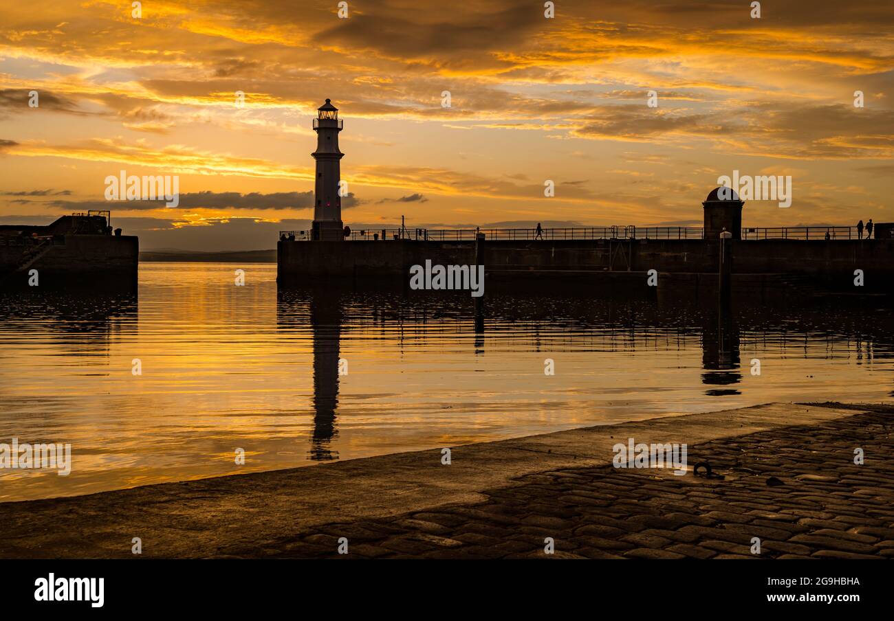 Il faro del porto di Newhaven si trova in un colorato cielo arancione al tramonto, Edimburgo, Scozia, Regno Unito Foto Stock