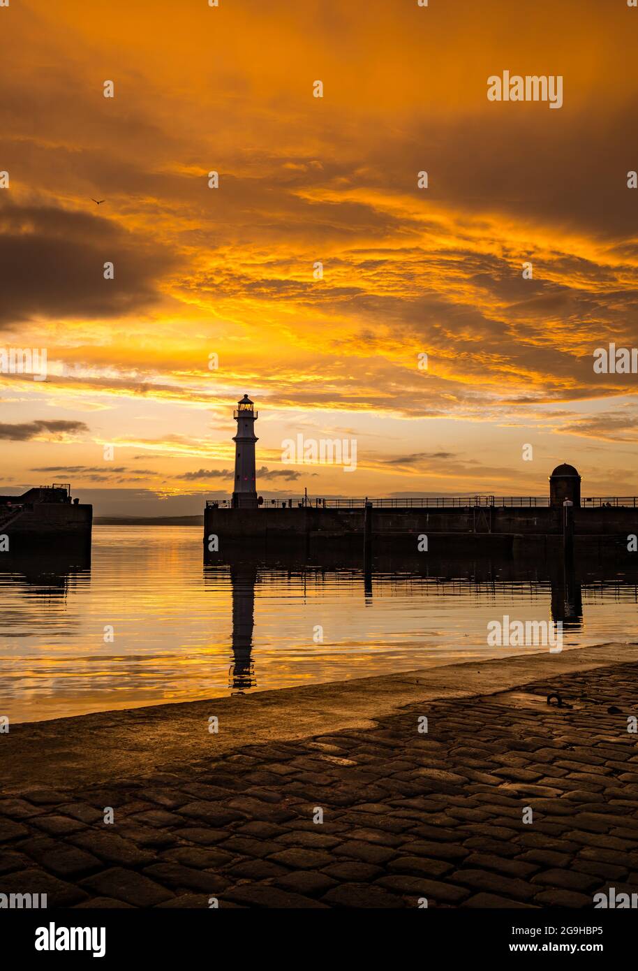 Il faro del porto di Newhaven si trova in un colorato cielo arancione al tramonto, Edimburgo, Scozia, Regno Unito Foto Stock