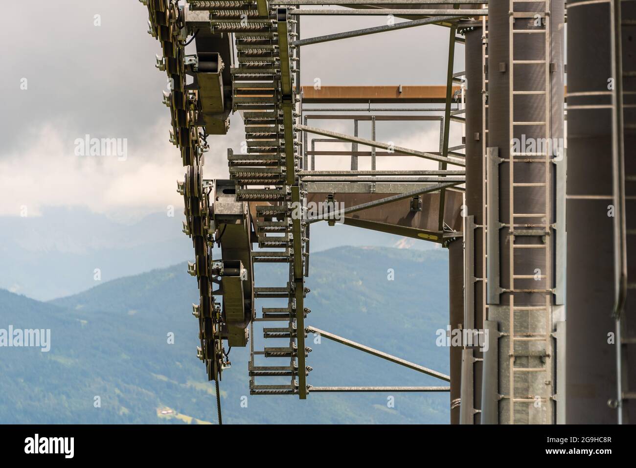 I dettagli di un nuovo impianto di risalita, funivia. Asta di supporto, fune, ruote, gradini, struttura in acciaio. Sullo sfondo panorama delle montagne. Foto Stock