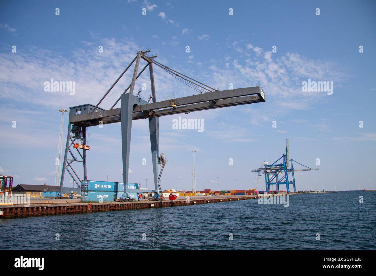 Terminal porta container con enorme gru vicino all'acqua. Cielo blu con sfondo nuvole sparse. Spazio di copia. Copenaghen, Danimarca - 25 luglio 2021. Foto Stock