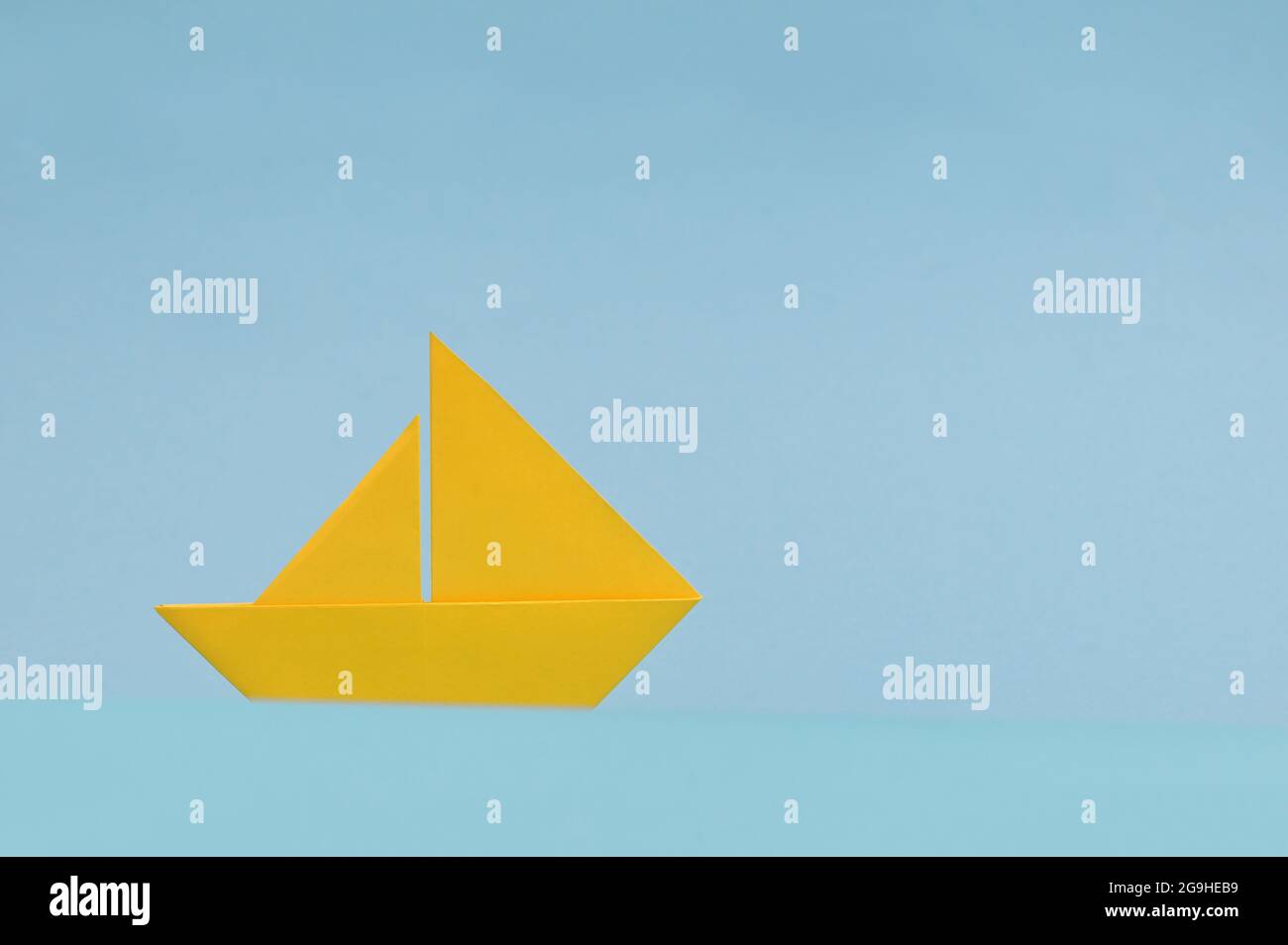 Concettuale Yellow Paper Boat su sfondo blu Foto Stock