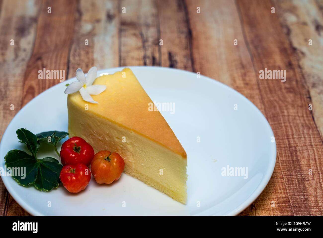 Vista ad alto angolo del Cheese Cake su un piccolo piatto bianco decorato con bacca rossa. Foto Stock
