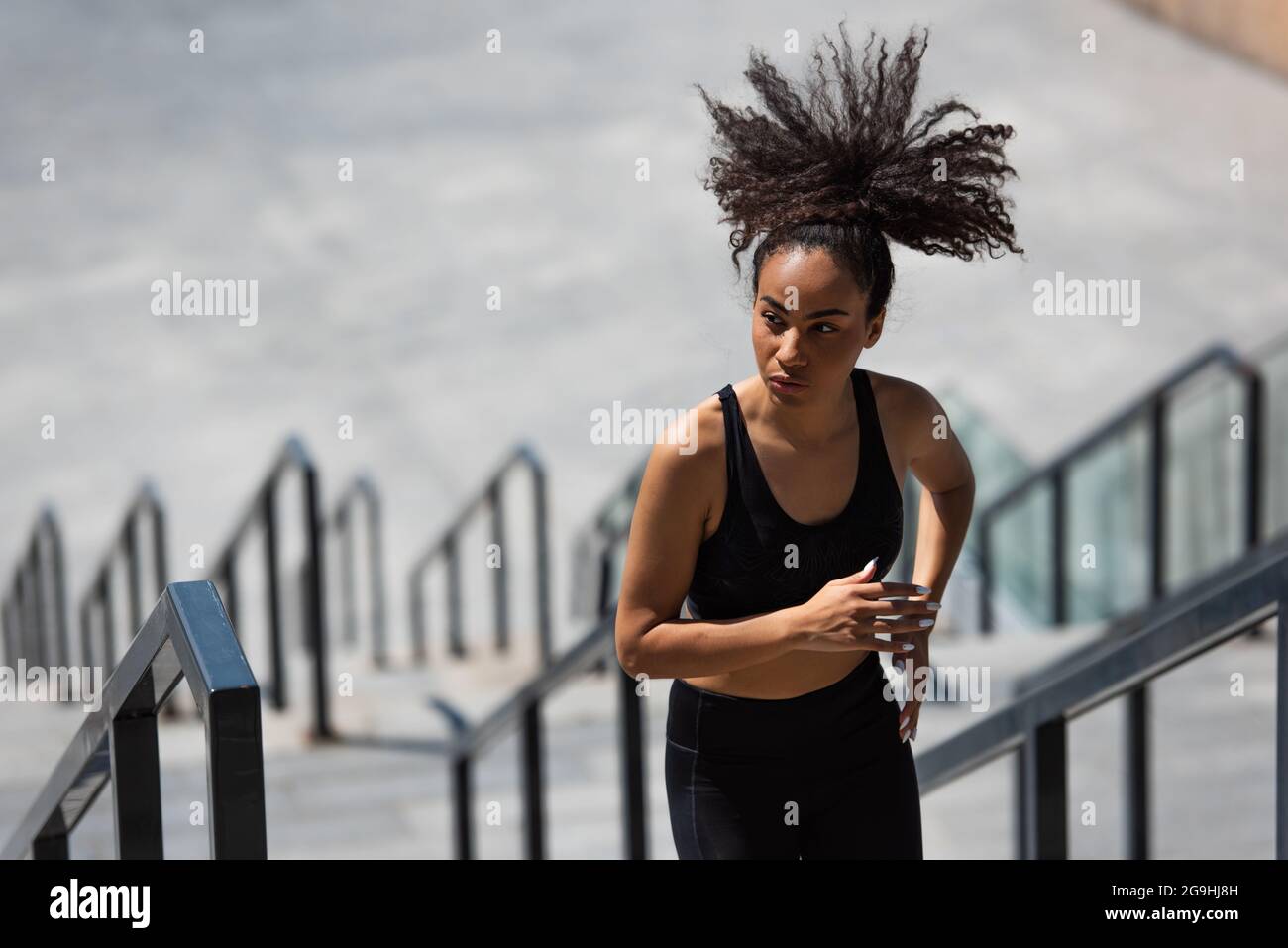 Donna africana ameriana con capelli afro che corrono sulle scale all'aperto Foto Stock