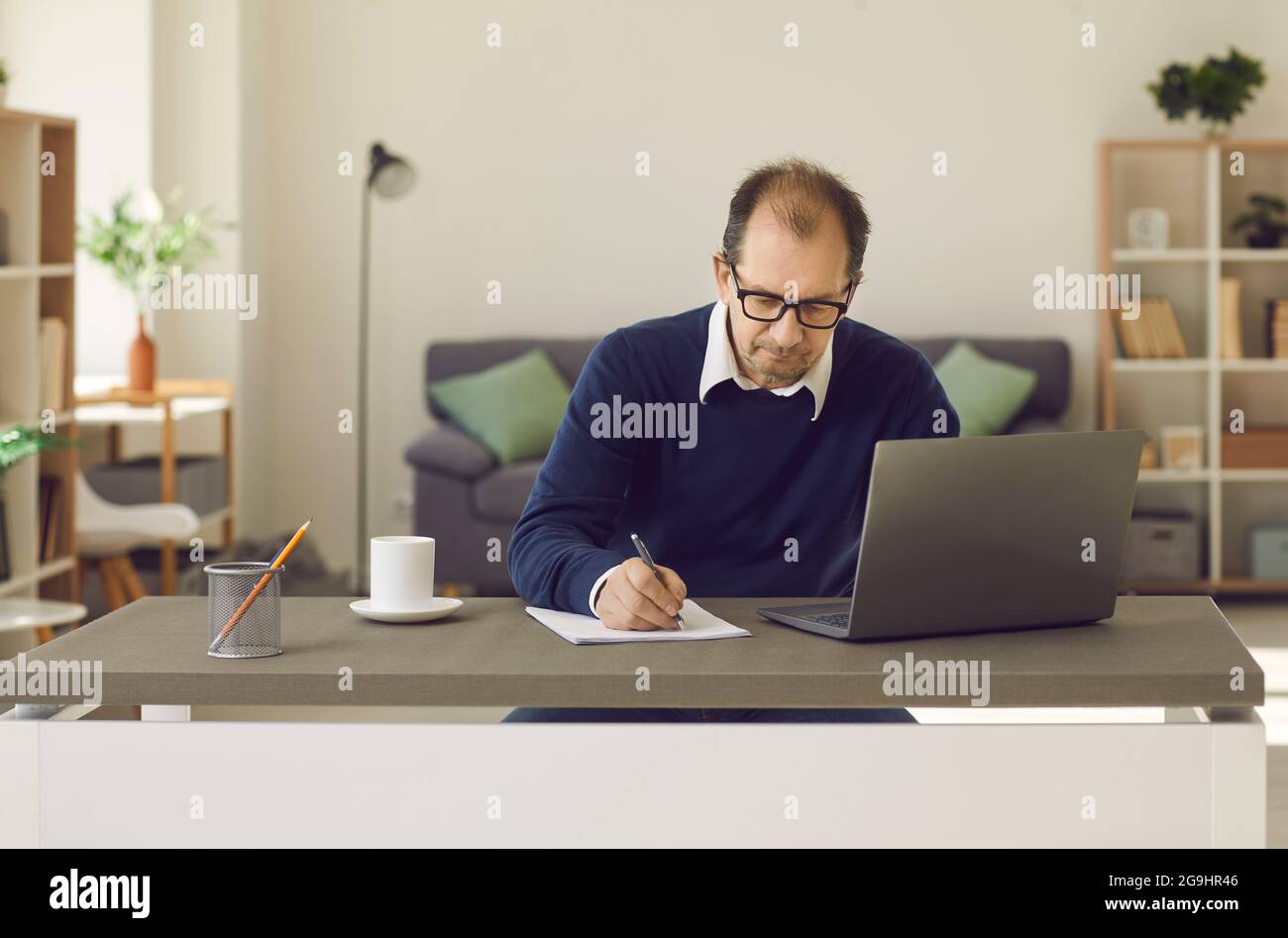 Uomo maturo seduto davanti allo schermo del computer portatile scrivendo su un ritratto del notebook cartaceo Foto Stock