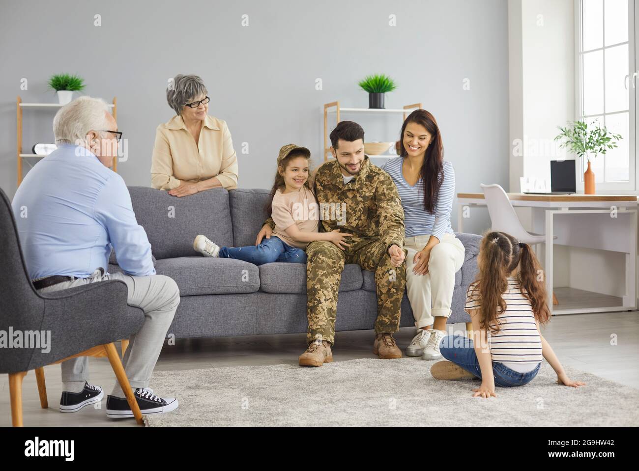 Soldato che è tornato a casa dal servizio militare parlando con la sua famiglia in soggiorno Foto Stock