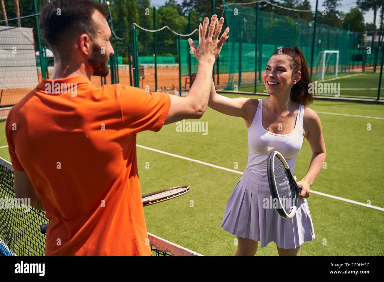 Gioiosa e affascinante sportswoman salutando il suo avversario prima della partita Foto Stock