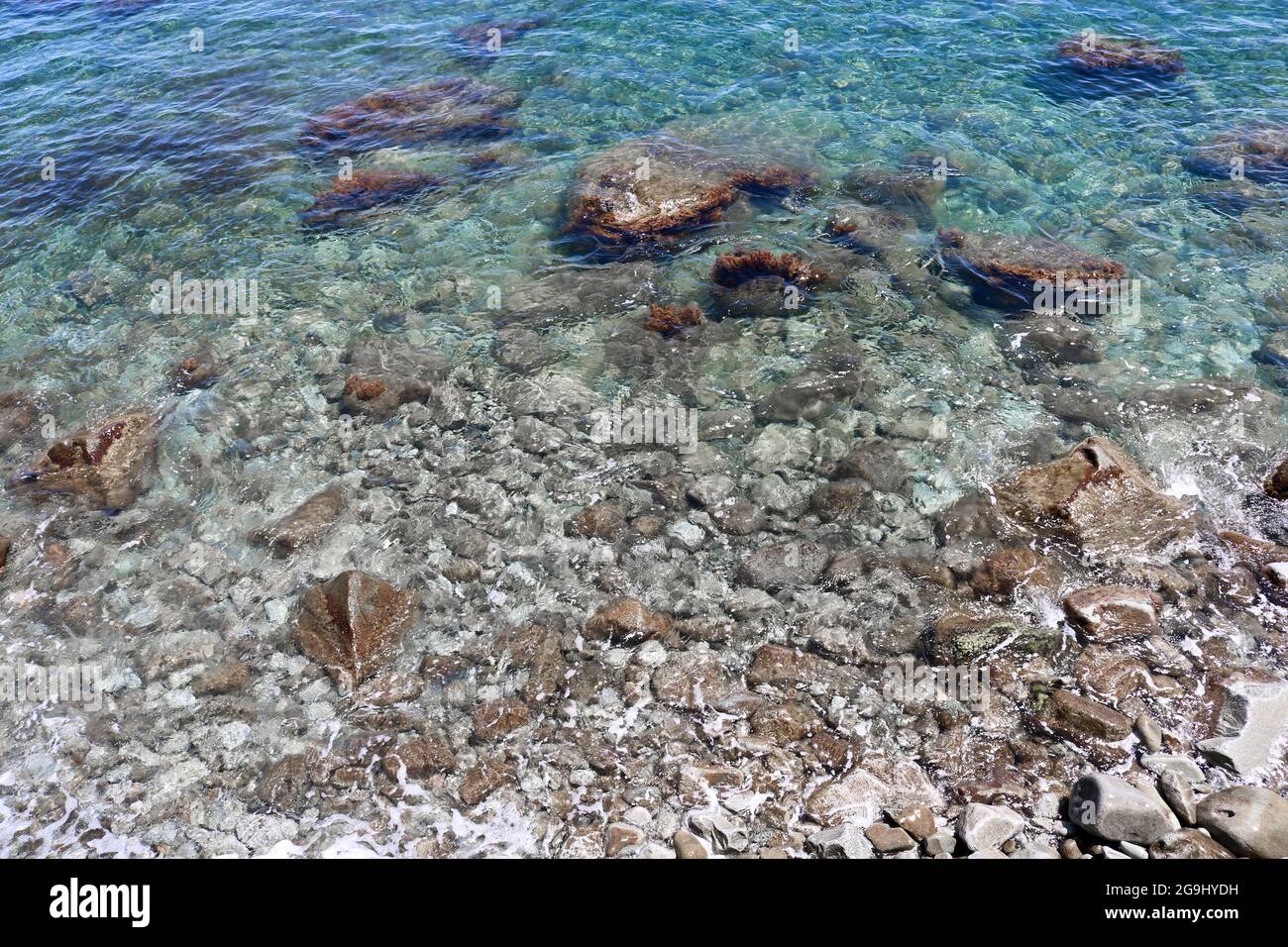 Fresco sfondo estivo - sabbia e ciottoli sotto acqua di mare trasparente. Immagine sfocata a causa del movimento dell'acqua. Spazio di copia. Foto Stock