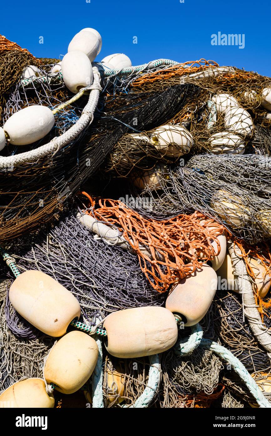 Una collezione di attrezzi da pesca commerciali in deposito sotto un cielo blu. Le corde per un modello ripetitivo contro reti e galleggianti Foto Stock