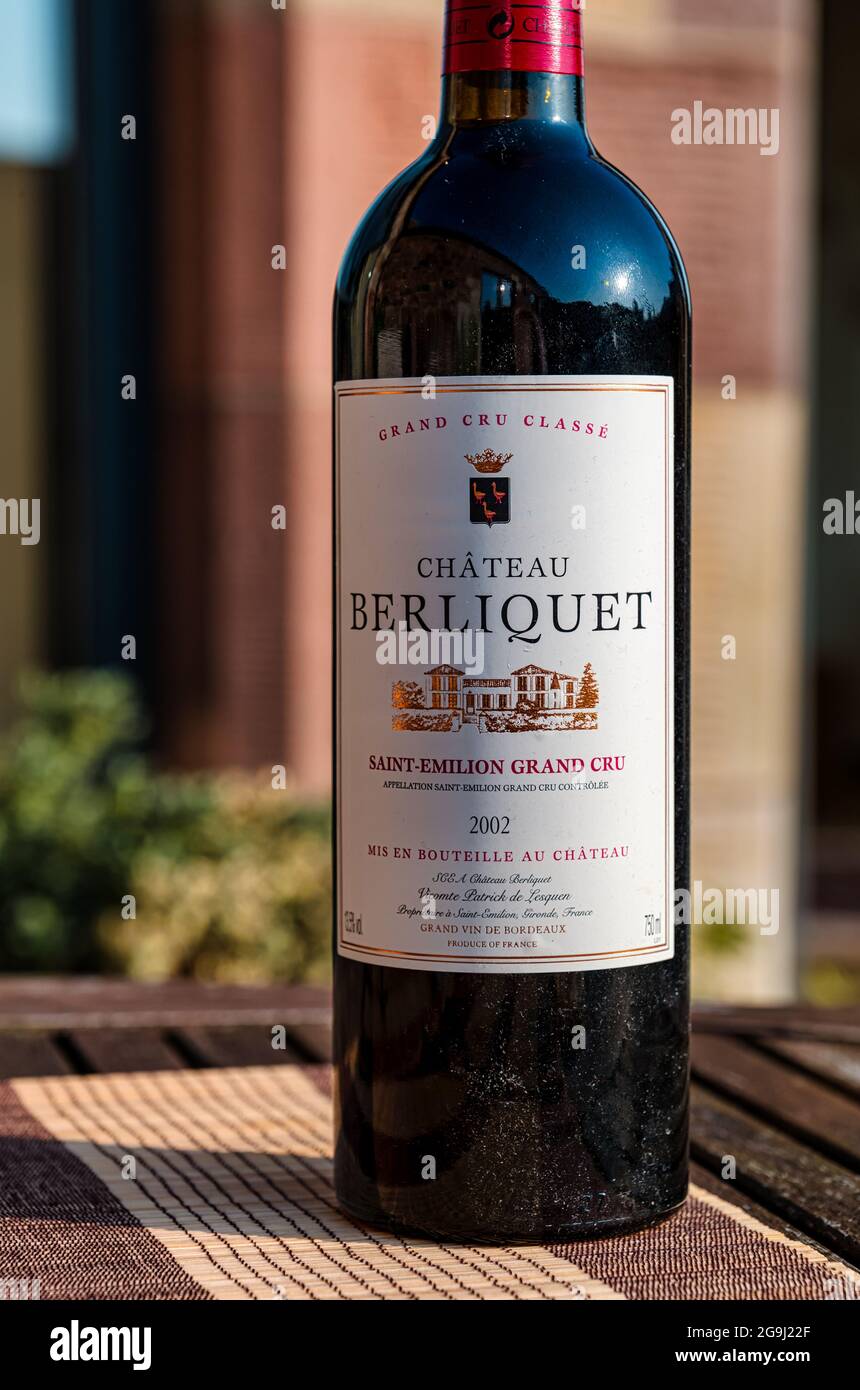 Bottiglia polverosa di vino rosso pregiato di qualità: Chateau Berliquet  2002 sul tavolo da patio all'aperto sotto il sole Foto stock - Alamy