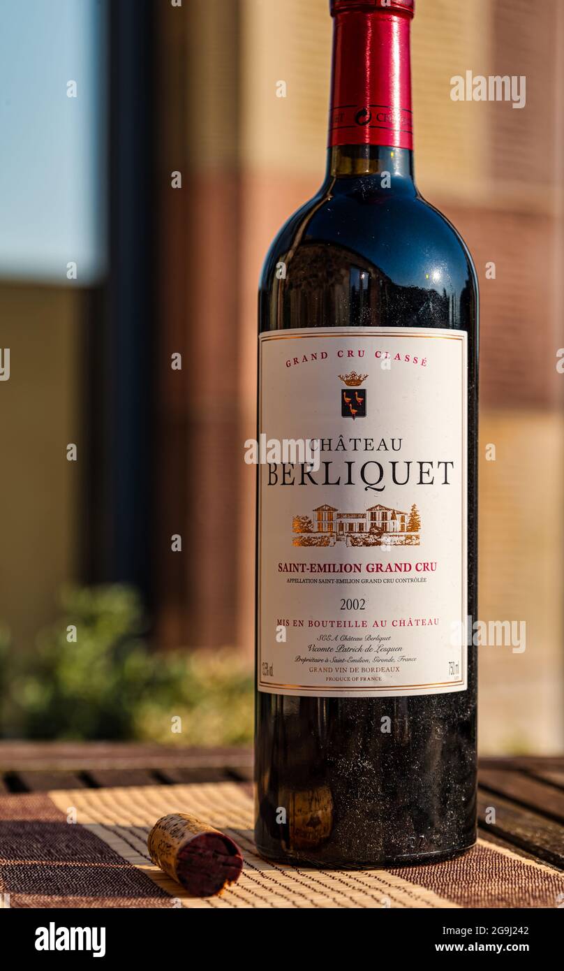 Bottiglia polverosa di vino rosso pregiato di qualità con sughero: Chateau Berliquet 2002 sul tavolo da patio all'aperto sotto il sole Foto Stock