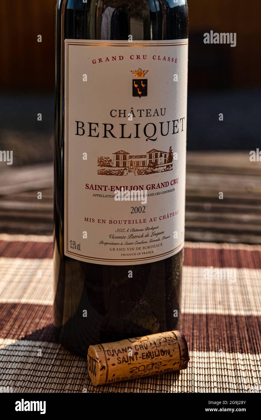 Bottiglia polverosa di vino rosso pregiato di qualità con sughero: Chateau Berliquet 2002 sul tavolo da patio all'aperto sotto il sole Foto Stock