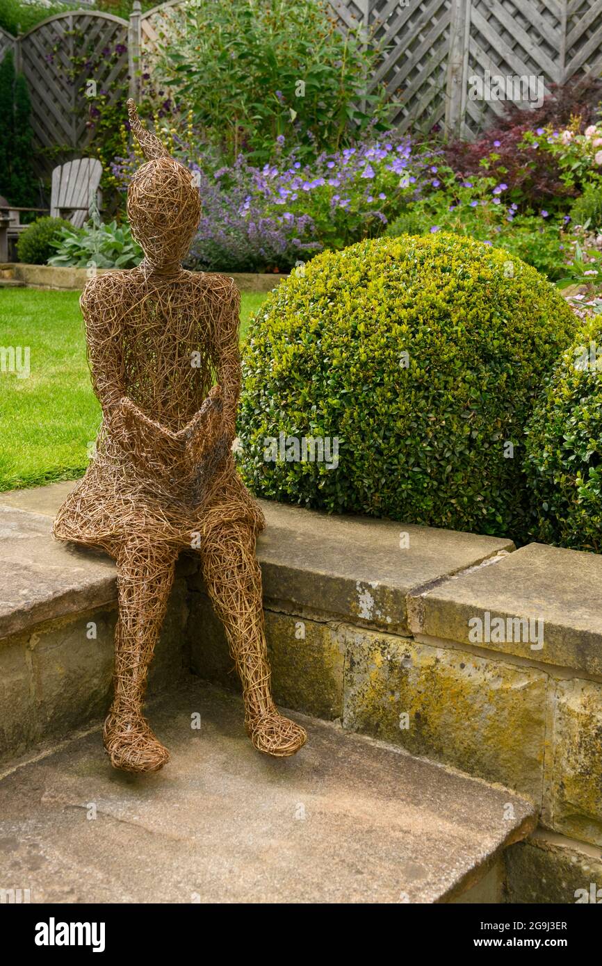 Willow scultura arte di ragazza (ornamentale) in bellissimo giardino paesaggistico (perenni fioriti, palline scatola, prato, ) - Yorkshire, Inghilterra, REGNO UNITO. Foto Stock