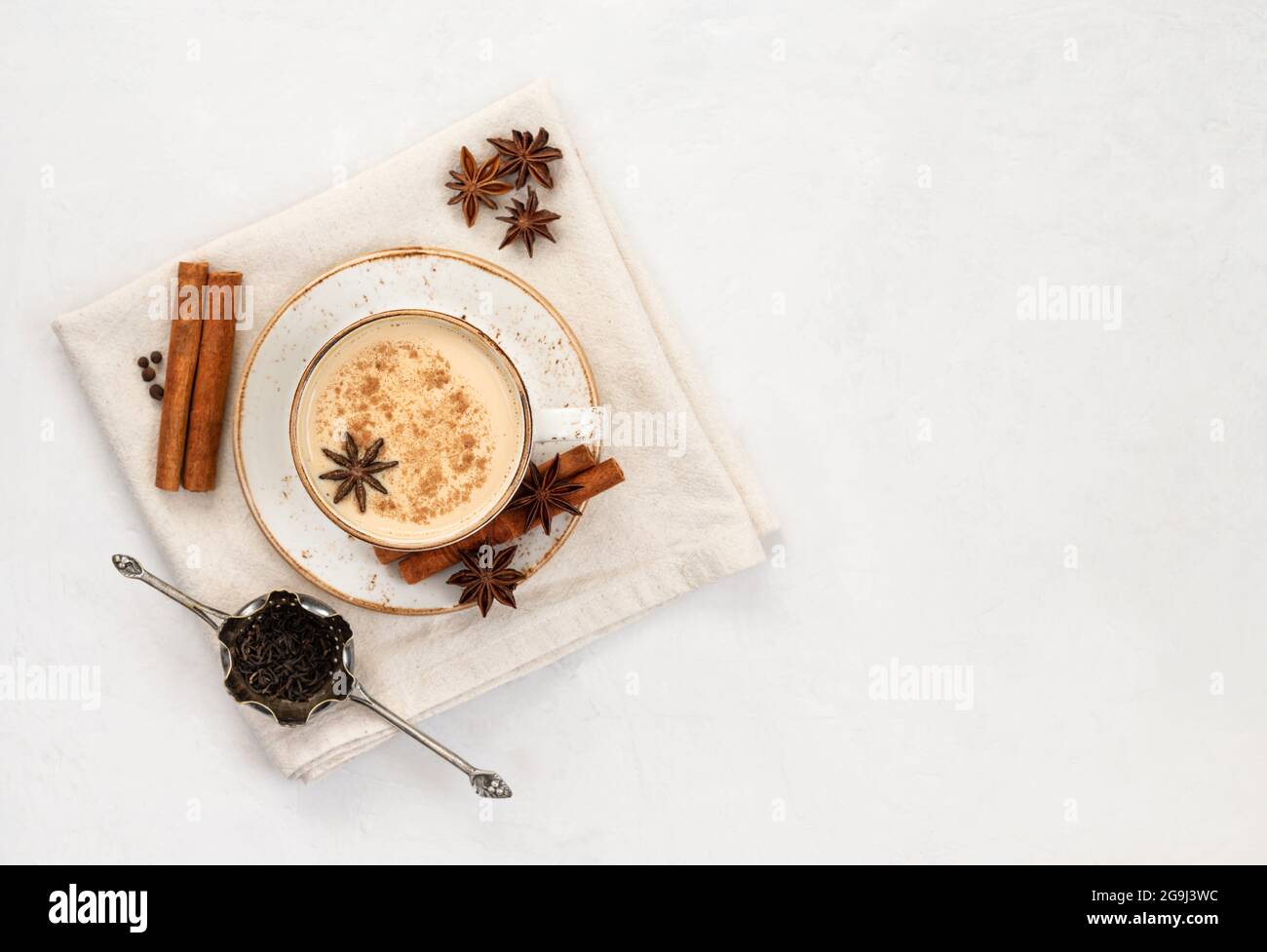 Tè Masala chai. Bevanda indiana tradizionale. Masala in una tazza bianca con un tovagliolo su uno sfondo bianco di cemento. Vista dall'alto. Spazio di copia. Foto Stock