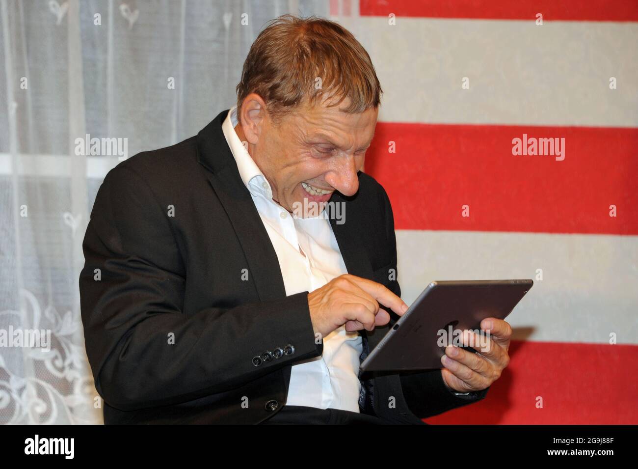 Monaco, Germania. 26 luglio 2021. L'attore Richy Müller scrive su un ipad nel ruolo di autistico Raymond Babbitt alla prova fotografica per il gioco 'Rain Man' al Komödie im Bayerischen Hof. Il gioco sarà eseguito dal 28 luglio al 15 agosto 2021. Credit: Ursula Düren/dpa/Alamy Live News Foto Stock