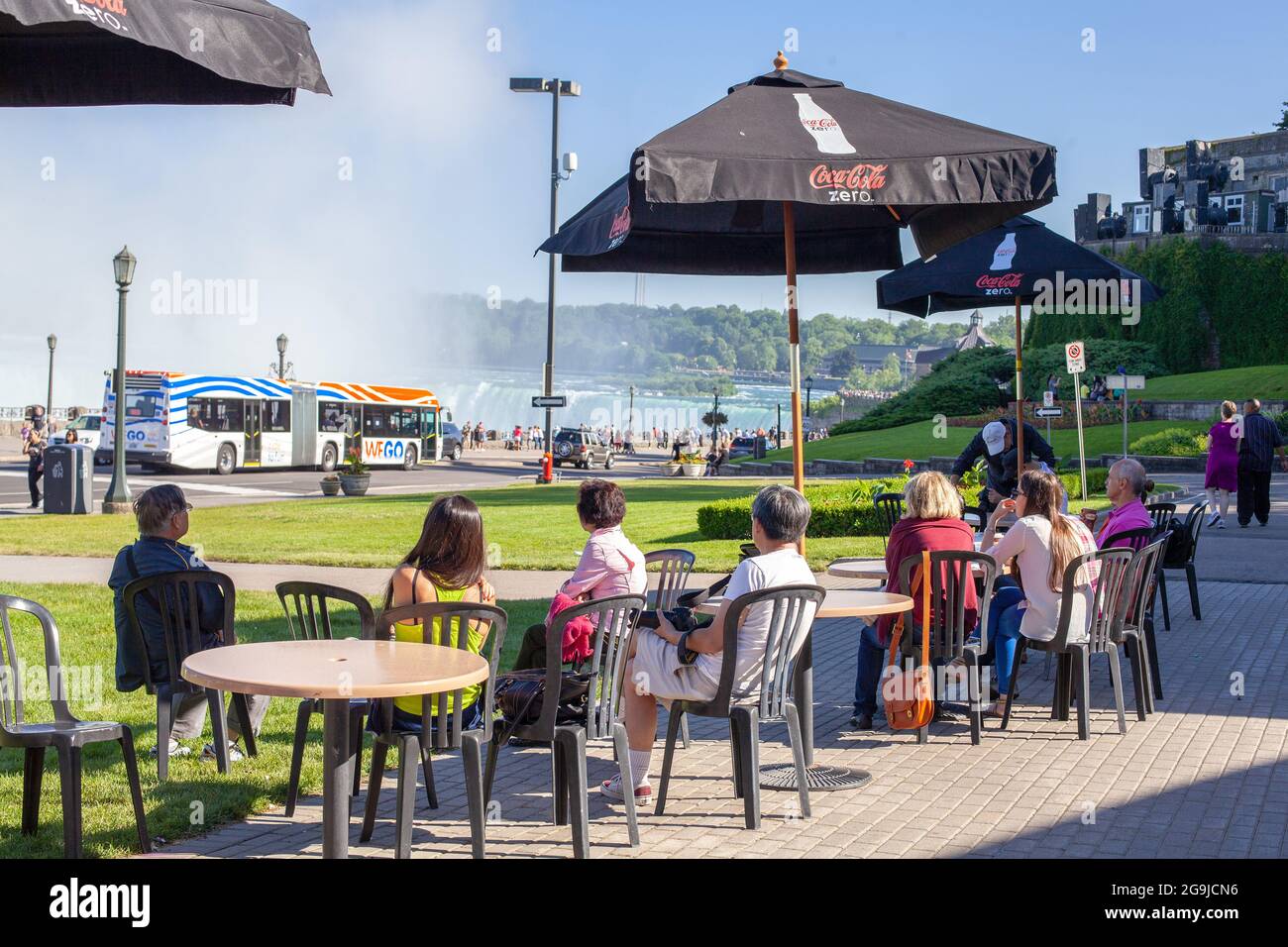 I turisti si sono seduti all'esterno in UN Cafe patio che guarda alle Cascate Horseshoe nelle Cascate del Niagara, Ontario Canada, UN autobus pubblico in background Foto Stock