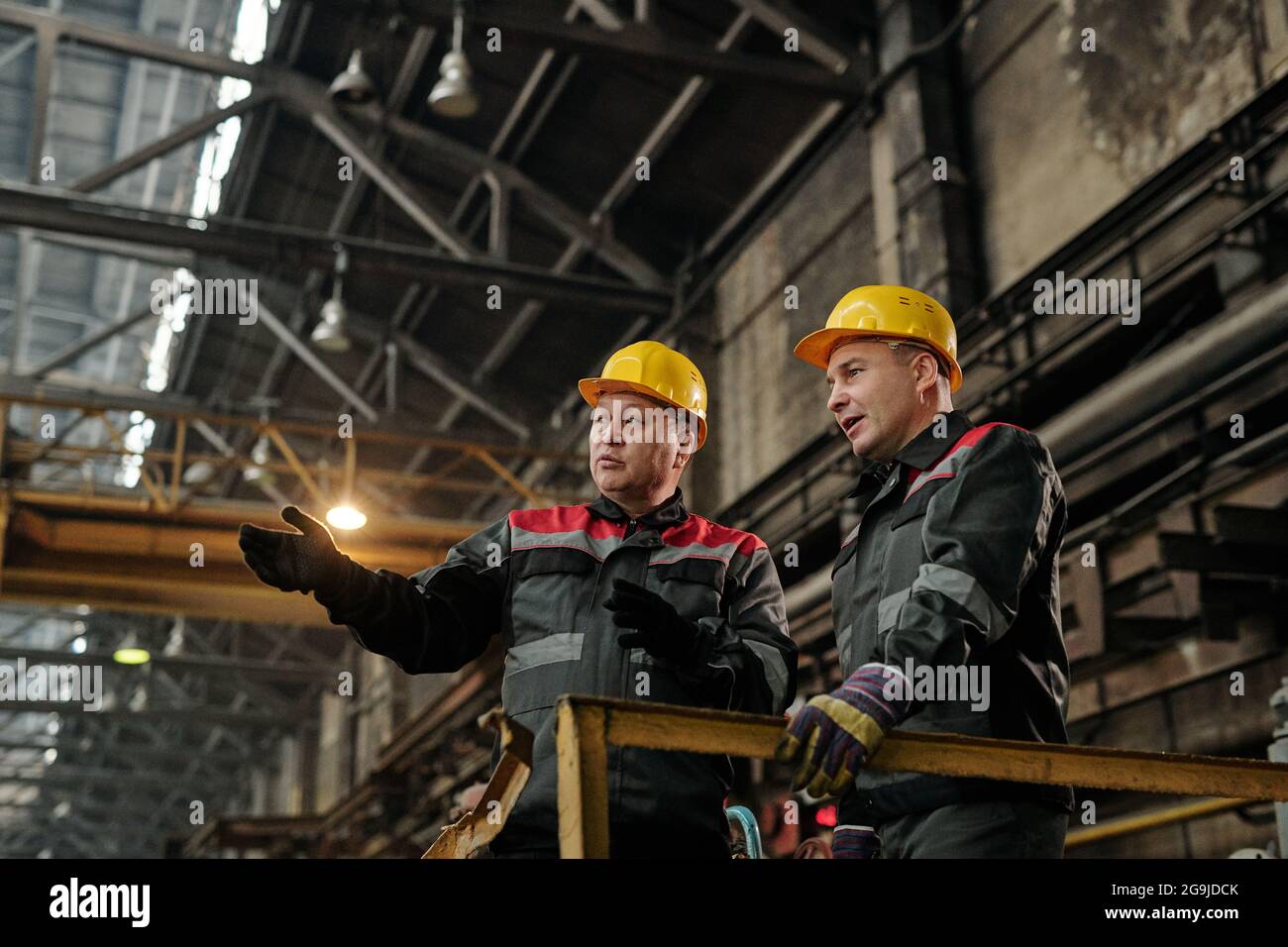Caposquadra che controlla il lavoro nell'impianto e ne discute con un lavoratore che utilizza un tablet digitale Foto Stock