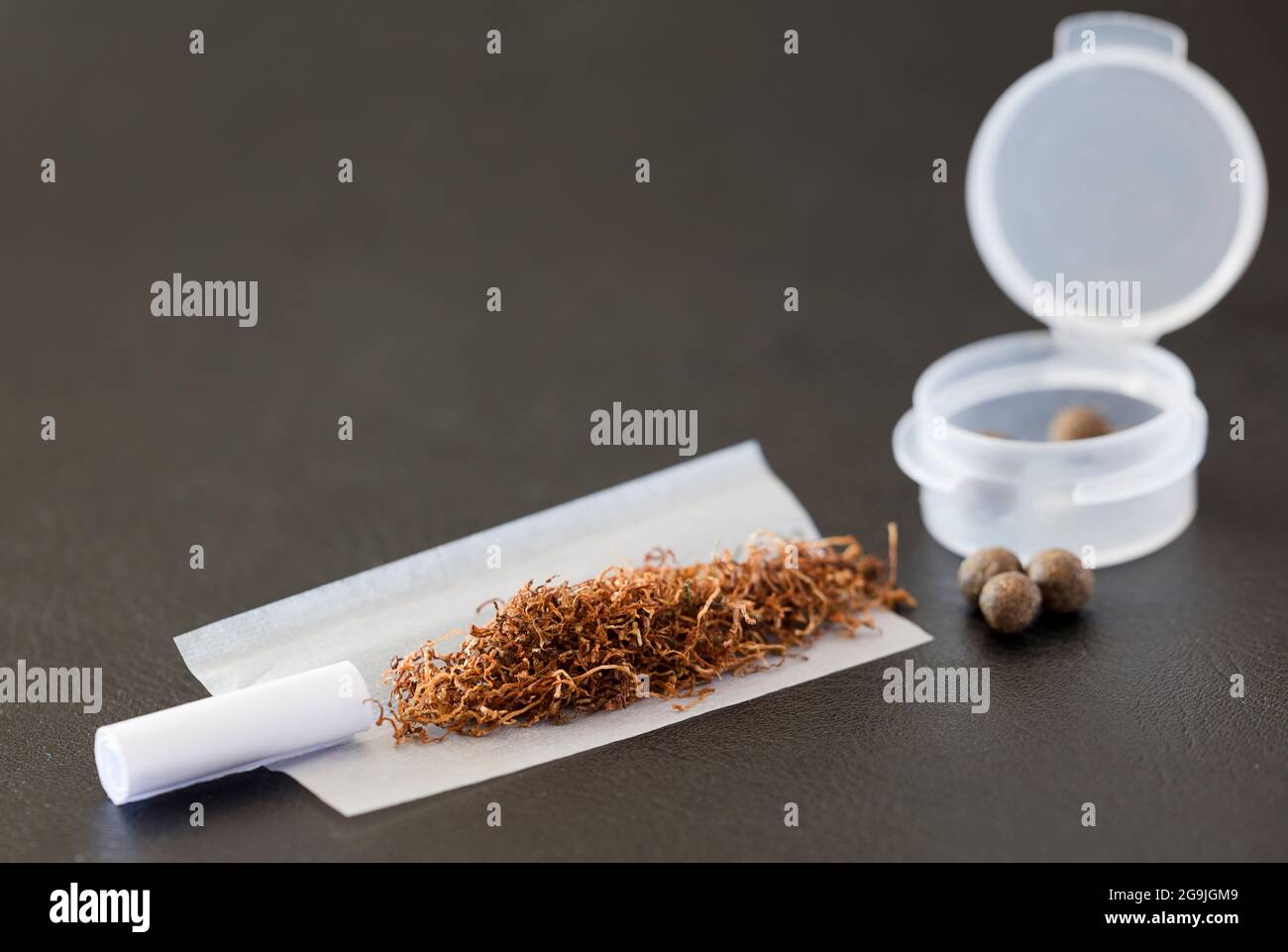 Preparazioni per sigari con hashish, filtro di cartone, carta, tabacco, contenitore di plastica e hashish Foto Stock