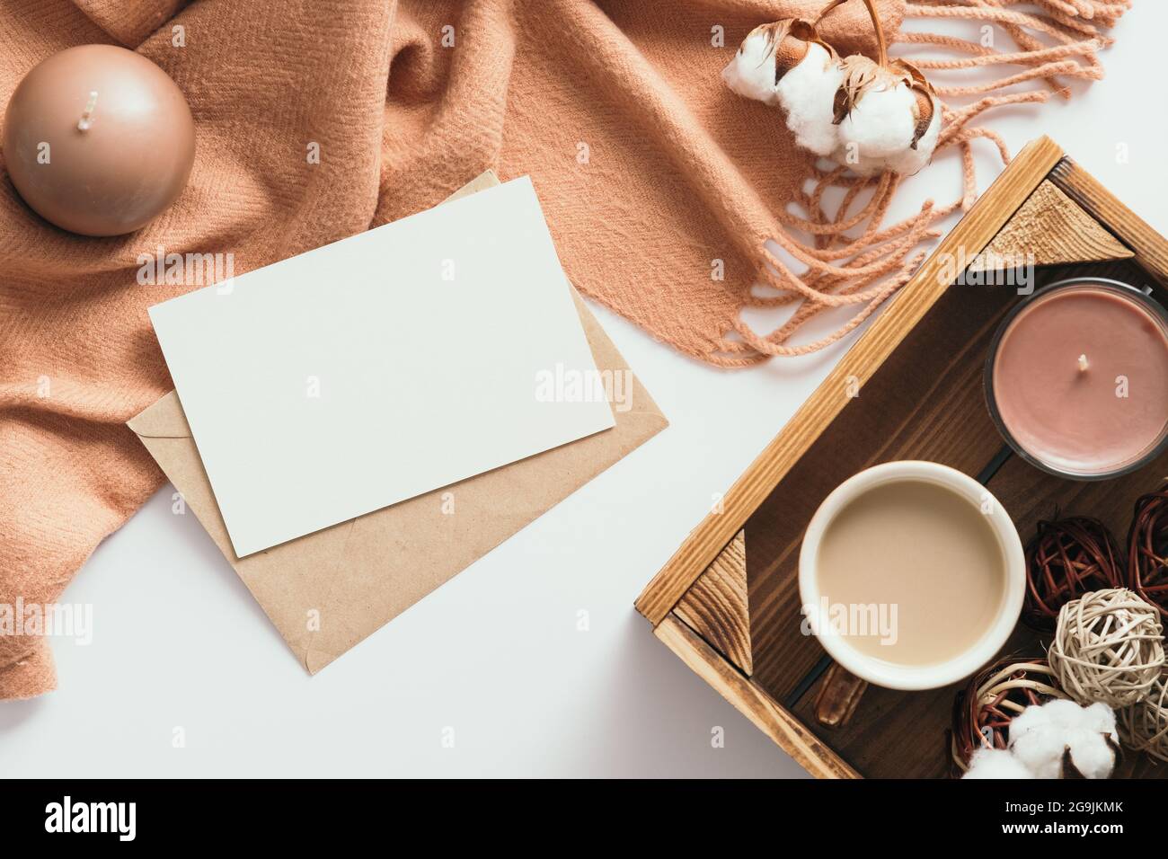 Composizione autunnale. Tavolo da lavoro femminile con lettera, carta bianca, sciarpa marrone, cotone su sfondo bianco. Disposizione piatta, vista dall'alto. Nordic, hygge, coz Foto Stock