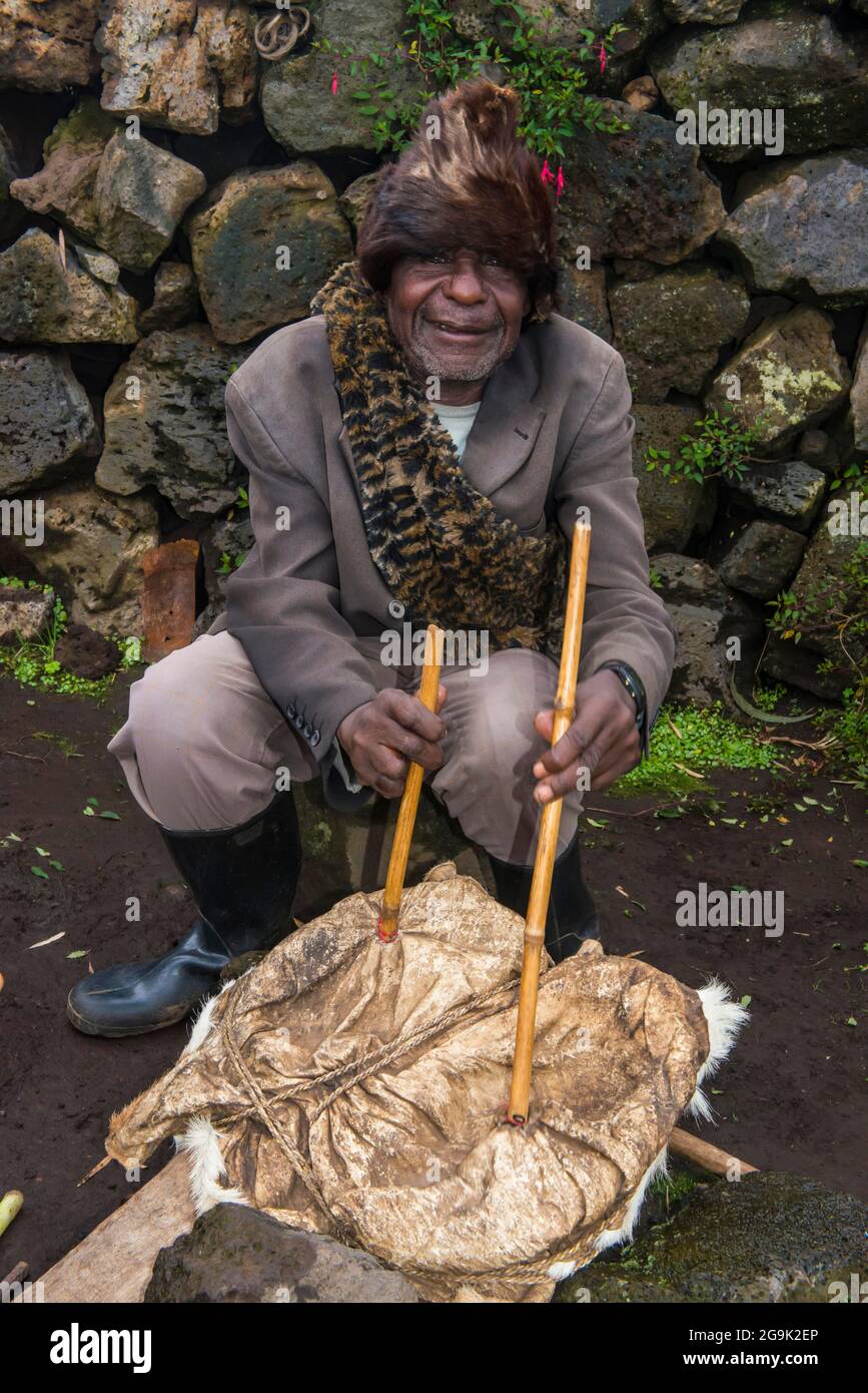 Uomo che usa la pelle animale per iniziare un fuoco in una cerimonia di ex bracconieri, nel Parco Nazionale di Virunga, Ruanda, Africa Foto Stock
