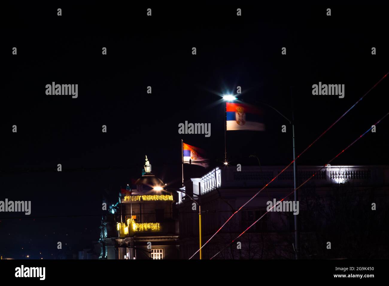Bandiere serbe, di notte, vento forte in cima all'edificio statale. Si svita in cima all'edificio di stato. Notte, vento forte. Foto Stock