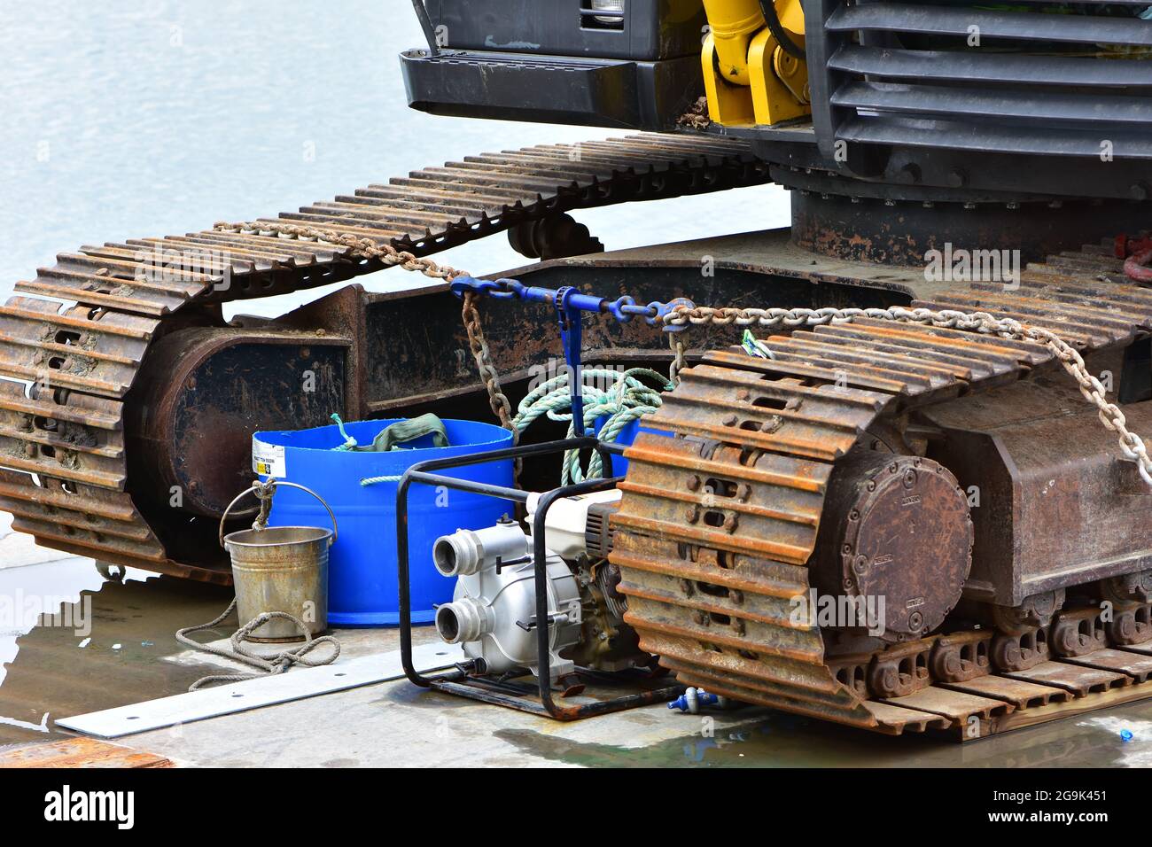 Dettaglio dei cingoli di un veicolo cingolato pesante con superficie d'acqua sullo sfondo. Foto Stock