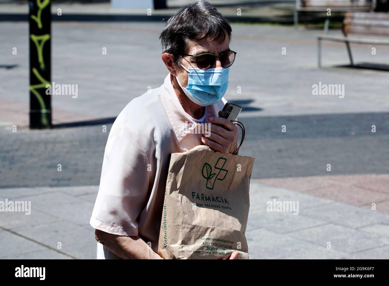 Donna mascherata innesti la sua borsa di farmaci, Barcellona, Spagna. Foto Stock